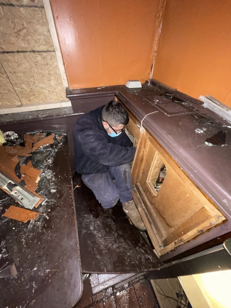Technician working on plumbing beneath a kitchen sink